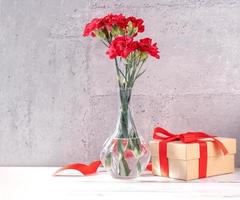 May mothers day handmade giftbox wishes photography - Beautiful blooming carnations with red ribbon box isolated on fair-faced gray background desk, close up, copy space, mock up photo