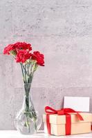 May mothers day handmade giftbox wishes photography - Beautiful blooming carnations with red ribbon box isolated on fair-faced gray background desk, close up, copy space, mock up photo