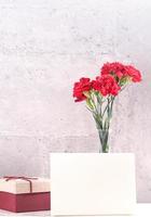 May mothers day handmade giftbox wishes photography - Beautiful blooming carnations with red ribbon box isolated on fair-faced gray background desk, close up, copy space, mock up photo