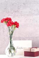 May mothers day handmade giftbox wishes photography - Beautiful blooming carnations with red ribbon box isolated on fair-faced gray background desk, close up, copy space, mock up photo