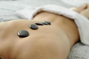 mujer joven recibiendo un masaje con piedras en un spa foto