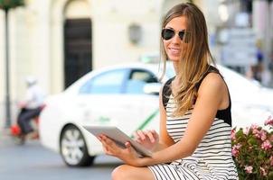 Atractiva mujer rubia con tablet PC de fondo urbano foto
