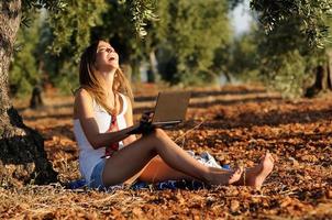 Girl with a laptop in a field in autumn photo
