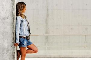 Young blonde woman against urban wall photo