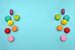 top view composition colored sweet French cakes macaroni cookies lie on an isolated blue background on sides of copy space in center. form of angel wings. Concept - happy birthday, Mother Day, March 8 photo