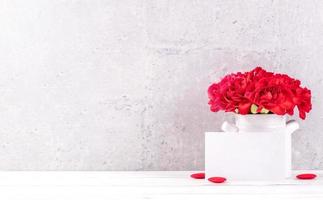la caja de regalo hecha a mano del día de las madres desea fotografía: hermosos claveles florecientes con una caja de cinta roja aislada en un escritorio de fondo gris de cara clara, primer plano, espacio de copia, maqueta foto