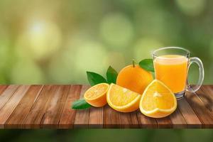 un vaso de jugo de naranja y naranjas en una mesa de madera con un fondo verde de naturaleza. foto