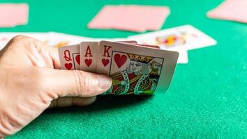 Closeup, man's hand holding cards in rummy play also called card game. Blurred background photo