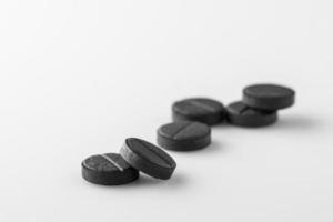 several black medical activated charcoal pills on white background. Isolated photo