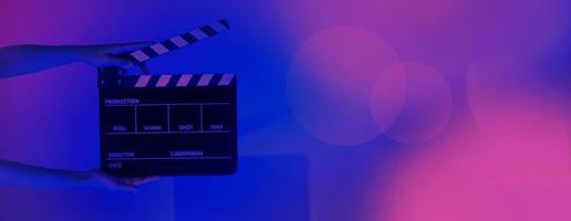 Hand holds empty film making clapperboard on color background in studio photo