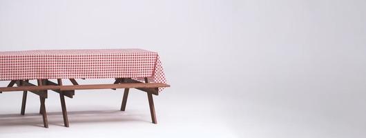 Picnic table and red checkered tablecloth with food and drink for outdoor party. Isolated photo