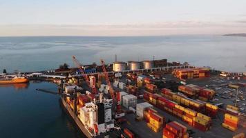 Batumi, Georgia, 2021 - Aerial tilt down view loaded cargo ship with freight containers docked by Batumi international seaport with black sea view on sunset video
