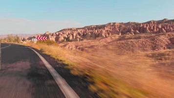 Panning close up driving on asphalt ground view scenic Cappadocia landscape . Front tire in fast motion with scenic desert landscape video