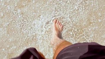 Male person feet view waking on wet salt lake barefoot in sunny day. Healthy procedures and benefits of salt video