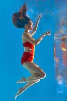 unbelievable, surreal, incredible, amazing underwater portrait of slim, fit woman in bright orange swimming suit