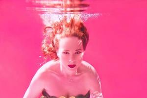 Surreal portrait of young attractive woman with air bubbles underwater in colorful water with ink in the swimming pool