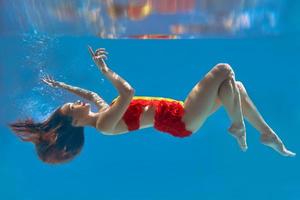 increíble, surrealista, increíble, sorprendente retrato submarino de una mujer delgada y en forma con traje de baño naranja brillante foto