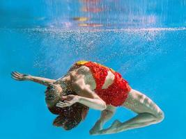 unbelievable, surreal, incredible, amazing underwater portrait of slim, fit woman in bright orange swimming suit photo