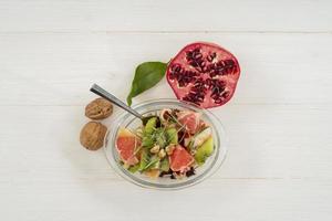 Fresh fruit salad with kiwi, pomegranate, grapefruit, and walnuts photo