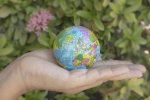 Woman hand holds the earth on blur background. The concept of Earth Day. photo
