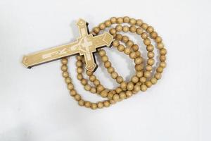 rosary beads with cross made of gray wood on a white background, selected focus on christ, narrow depth of field. photo