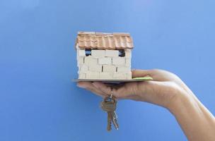 mano de una mujer sosteniendo una pequeña casa con llaves. foto
