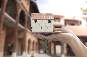 mano de una mujer sosteniendo una pequeña casa con llaves. foto