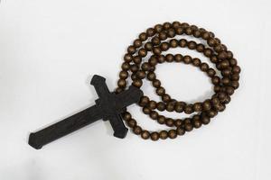 rosary beads with cross made of black wood on a white background, selected focus on christ, narrow depth of field. photo