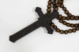 rosary beads with cross made of black wood on a white background, selected focus on christ, narrow depth of field. photo