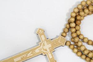 rosary beads with cross made of gray wood on a white background, selected focus on christ, narrow depth of field. photo