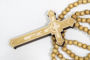 rosary beads with cross made of gray wood on a white background, selected focus on christ, narrow depth of field. photo