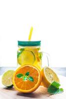 Lemonade of orange, lemon, lime and mint on the background of the contour sunlight. photo