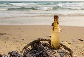 vieja botella de bebida en desuso en la playa foto