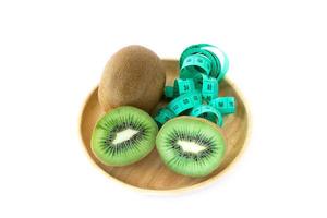 fresh kiwi and measuring tape in wooden pate photo
