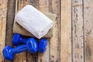 Blue dumbbells and towel on wooden table. photo