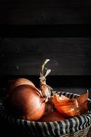 Onions in a wicker basket with wooden boards in the background. Rustic style. Vertical image. photo