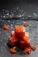 Tuna sashimi dipped in soy sauce with salmon roe, thick salt and dill on slate stone. Raw fish in traditional Japanese style. Vertical image. photo