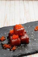 Tuna sashimi dipped in soy sauce with salmon roe, thick salt and dill on slate stone. Raw fish in traditional Japanese style. Vertical image. photo