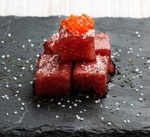 Tuna sashimi dipped in soy sauce with salmon roe, thick salt and dill on slate stone. Raw fish in traditional Japanese style. Horizontal image. photo