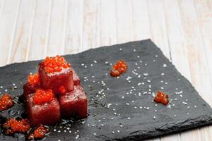 Tuna sashimi dipped in soy sauce with salmon roe, thick salt and dill on slate stone. Raw fish in traditional Japanese style. Horizontal image. photo