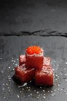 Sashimi de atún bañado en salsa de soja con huevas de salmón, sal gruesa y eneldo sobre piedra de pizarra. pescado crudo al estilo tradicional japonés. imagen vertical foto