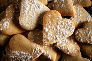 Delicious home-made heart-shaped cookies sprinkled with icing sugar on sackcloth and wooden boards. Horizontal image seen from above. photo