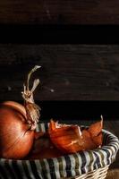 cebollas en una canasta de mimbre con tablas de madera en el fondo. estilo rústico imagen vertical foto