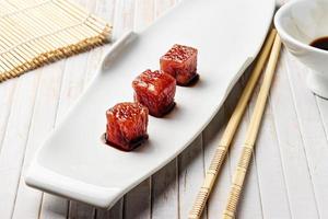 Tuna sashimi dipped in soy sauce with chopsticks and bamboo mat. Raw fish in traditional Japanese style. Horizontal image. photo