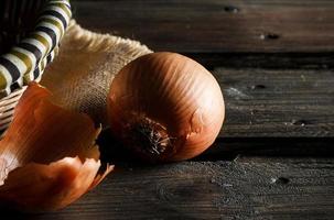 Onion seen close up with wicker basket and sackcloth on wooden boards. Rustic style. Horizontal image. photo