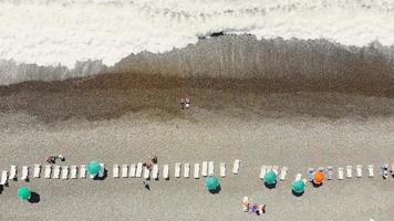 Luchtfoto van boven naar beneden vlieg over toerist op het strand van Sarpi in Batumi, genietend van de zomer op een warme zonnige dag video