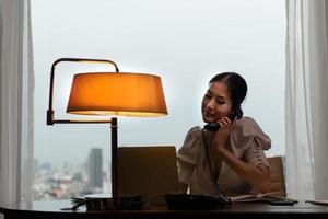 una joven empresaria supervisa y realiza un seguimiento de las tareas en su oficina con un paisaje urbano en el fondo de su escritorio. foto