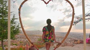 Chica caucásica de ensueño en los famosos columpios de Capadocia disfrutar del atardecer en Turquía video