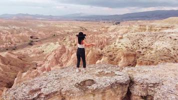 luchtcirkel rond jonge kaukasische zorgeloze vrouw die danst in de beroemde reisbestemming Cappadocië met schilderachtige sprookjesachtige schoorstenen panorama in devrent-vallei video