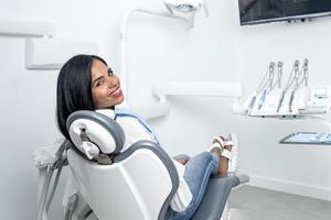 mujer sentada en una silla en una clínica dental frente a la cámara